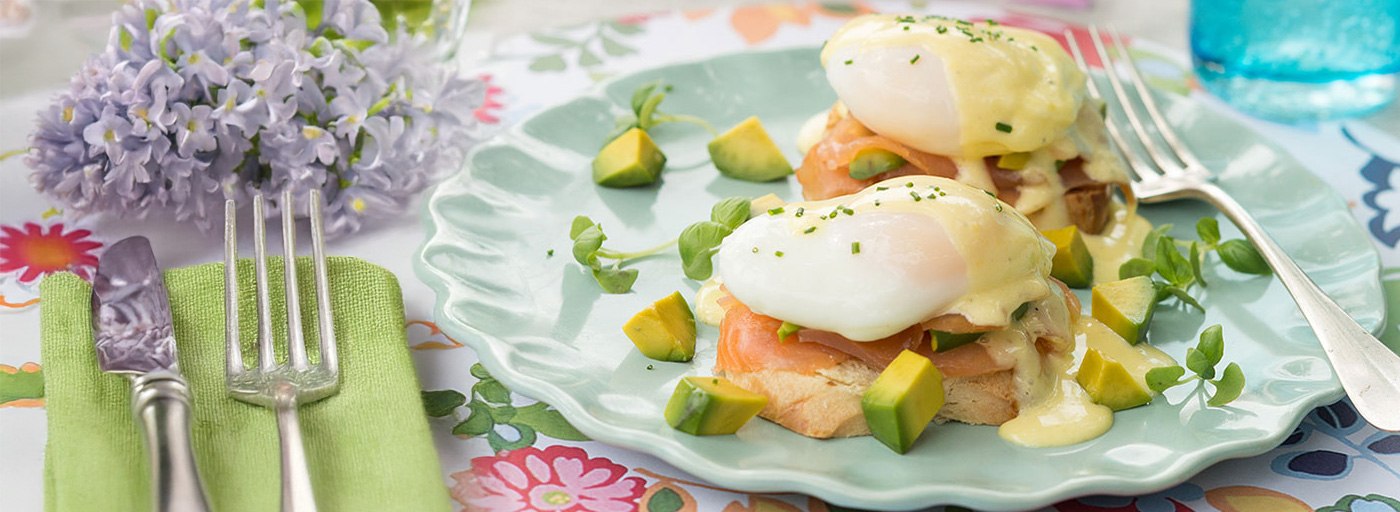 view of delicious eggs benedict on a spring tablescape with flowers, image by Gourmet Food Store